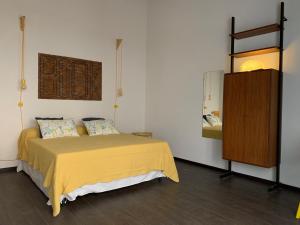 a bedroom with a yellow bed and a wooden cabinet at Casa VerbaVolant in Siracusa