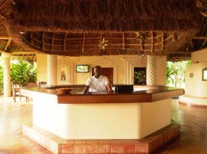 a man sitting at a bar in a resort at Neptune Palm Beach Boutique Resort & Spa - All Inclusive in Galu