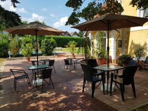 a patio with tables and chairs and umbrellas at Éden Villa Apartmanház in Balatonfüred