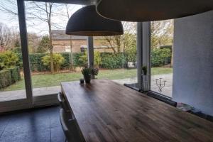 a dining room with a wooden table and large windows at Bed & Wellness Boxtel, luxe kamer met airco en eigen badkamer, ligbad in Boxtel