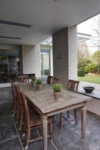 una mesa de madera y sillas en un patio en Bed & Wellness Boxtel, luxe kamer met airco en eigen badkamer, ligbad, en Boxtel