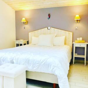 a bedroom with a large white bed with two tables at Les Arums de Sanguinet in Sanguinet