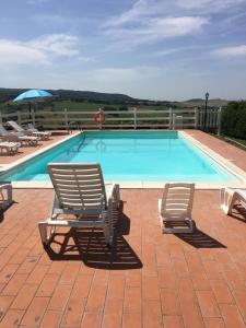 uma piscina com duas espreguiçadeiras e um guarda-sol em Casale Poggio Meone em Santa Luce