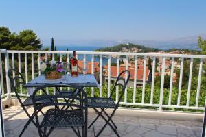 a table with two chairs and a bottle of wine on a balcony at Apartment Siesta in Cavtat