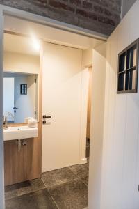 a bathroom with a door leading to a sink at B&B Gitsdal in Hooglede