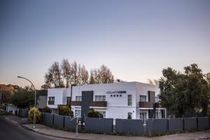 un edificio blanco con una valla delante en Adelante Lodge, en Bloemfontein