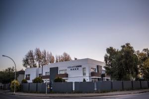 un edificio blanco con una valla delante en Adelante Lodge, en Bloemfontein