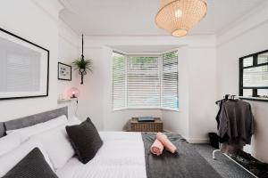 1 dormitorio con cama blanca y ventana en Nomi Homes - Exeter - BOOKDIRECT - Central - BEACH - WIFI, en Exeter