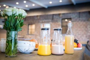 Tres botellas de zumo de naranja y un jarrón de flores. en B&B Gitsdal, en Hooglede
