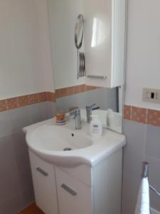 La salle de bains est pourvue d'un lavabo blanc et d'un miroir. dans l'établissement La dimora, à Vietri