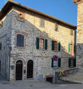 a stone building with green shutters and a bike parked outside at Dolcevita Chianti Apartments in Radda in Chianti