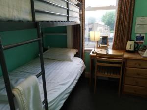 a bedroom with a bunk bed and a desk and a window at Twin Lions Hotel in Edinburgh