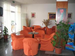 una sala de estar con sillas naranjas y una mesa en Hotel Playa, en Rímini