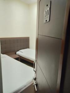 
a room with a white refrigerator and a white bed at Hotel Alka in Varanasi
