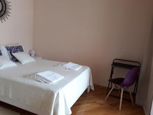 a bedroom with a white bed and a chair at Lila apartmani in Baošići +27 photos