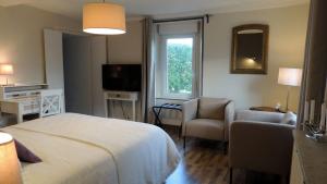 Un dormitorio con una cama y una silla y un televisor. en Le Jardin Du Puits, en Longueville