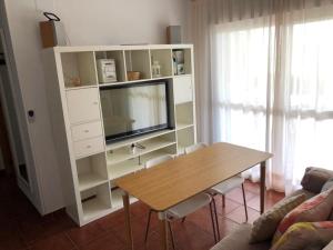 sala de estar con TV y mesa de madera en Las Dunas De Islantilla en Islantilla