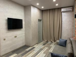 a living room with a couch and a television on a wall at Loft Batumi in Batumi