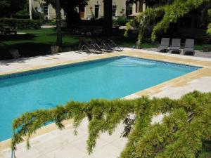 una piscina con sillas y palmeras en un patio en Gites du Caylar - Chambres et Appartments en Le Caylar