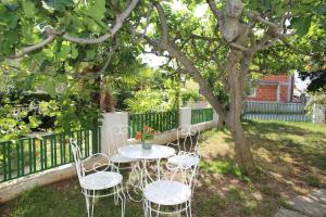 uma mesa e cadeiras debaixo de uma árvore num quintal em Apartments Fjaka em Sveti Filip i Jakov