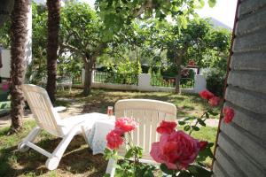 uma cadeira branca e flores cor-de-rosa num quintal em Apartments Fjaka em Sveti Filip i Jakov