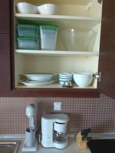 un armario con platos y cuencos en una encimera de cocina en Fotini's Apartment en Néa Péramos