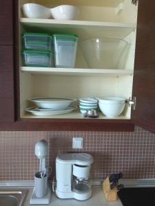 a cupboard with plates and bowls on a kitchen counter at Fotini's Apartment in Nea Peramos +24 photos