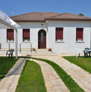 uma casa branca com uma porta vermelha e um pátio em B&B La Via dell'Ambra em Due Carrare