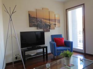 - un salon avec une télévision et une chaise bleue dans l'établissement Porto 2 Bedroom Beach Apartment, à Matosinhos