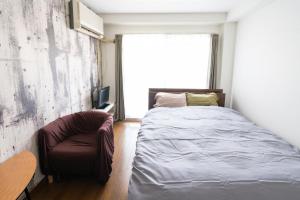 a bedroom with a bed and a chair and a window at Dazaifu - Apartment / Vacation STAY 36647 in Dazaifu