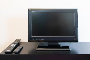 um monitor de computador e dois comandos remotos numa secretária em Dazaifu - Apartment / Vacation STAY 36942 em Dazaifu