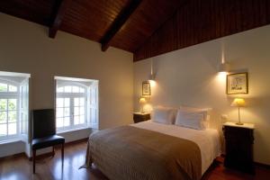 a bedroom with a bed and two windows at Quinta de Lograssol in Mealhada