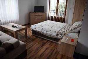 a bedroom with a bed and a tv and a couch at Apartment and rooms Konak in Višegrad