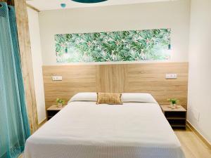 a bedroom with a white bed with a painting on the wall at Garnica5 Suites in Torrelavega