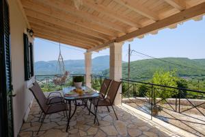 SokrákionにあるKoukoutsa House with Swimming Pool Corfu Sokrakiのバルコニーにテーブルと椅子が置かれたパティオ