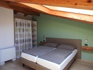 1 dormitorio con cama y techo de madera en Appartamenti Tasel with heated Pool, en Malcesine