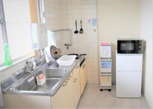 una pequeña cocina con fregadero y nevera. en Kamiyama Mansion / Vacation STAY 4357, en Osaka
