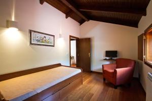 a bedroom with a bed and a red chair at Quinta de Lograssol in Mealhada