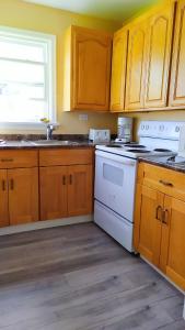 a kitchen with wooden cabinets and a white stove top oven at Lunge Haven Cottages & Boating Club in Lindsay