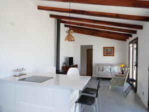 uma cozinha e sala de estar com paredes brancas e tectos em madeira em Casa Viges em El Pinar del Hierro