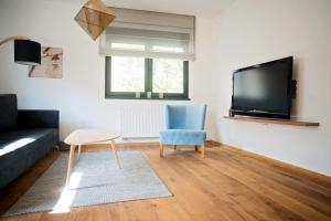 a living room with a blue chair and a tv at Luna Deluxe City Center & Free Parking in Sarajevo