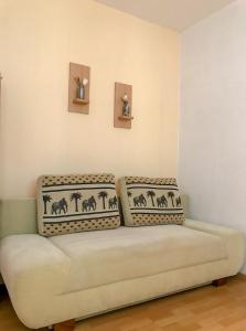 ein Sofa in einem Zimmer mit zwei Bildern an der Wand in der Unterkunft Beach Paradise Apartments in Liepāja