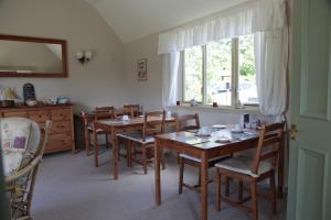 una sala da pranzo con tavoli, sedie e una finestra di Dunchraigaig House a Kilmartin