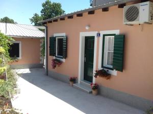 a house with green shutters and flowers on it at Apartments Odrina in Split