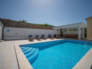 a swimming pool with blue water in a yard at Apartment Josipa-2 by Interhome in Klenovica