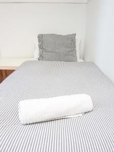 Una cama blanca con una manta blanca. en Pension Aussie Guesthouse, en San Sebastián
