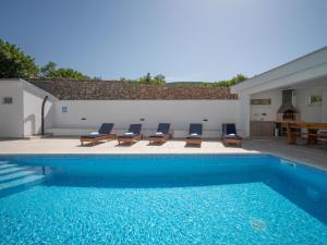 a swimming pool with a group of chairs and a table at Apartment Josipa-2 by Interhome in Klenovica