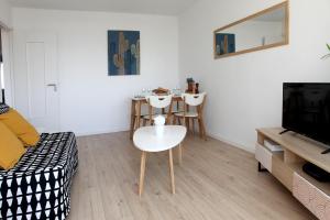 a living room with a table and a white chair at Résidence La Corvette in Toulon