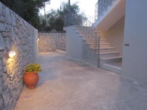 a patio with a stone wall and a plant in a pot at Blue Yard Apartments in Kalamata