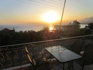 a table and chairs on a balcony with the sunset at Blue Yard Apartments in Kalamata
